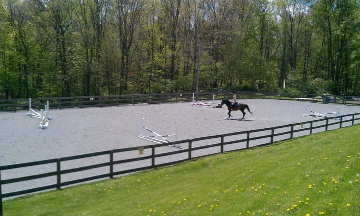 Rider in outdoor ring with jumps